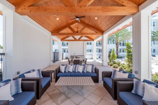 a covered patio with blue chairs and a wooden ceiling