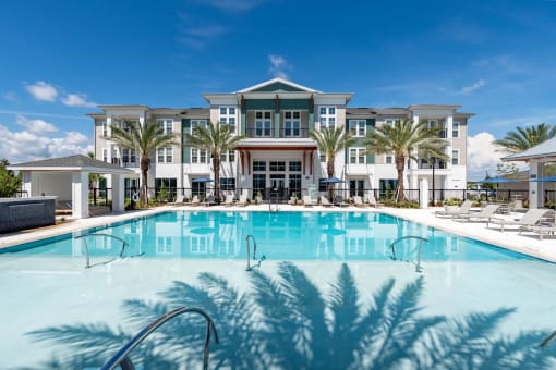 a large swimming pool in front of a building with palm trees