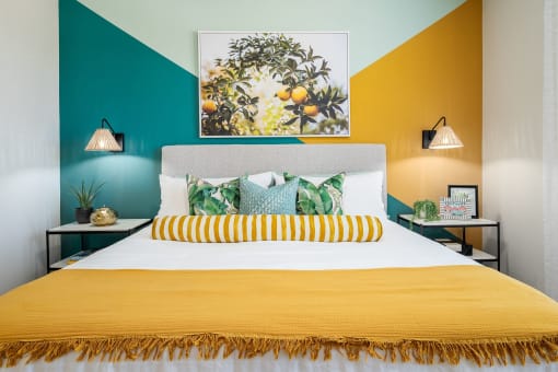 a bedroom with a yellow bed and a green wall and a painting on the wall