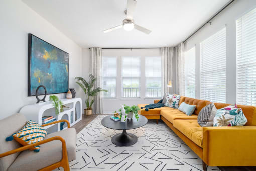 a living room with a yellow couch and a ceiling fan