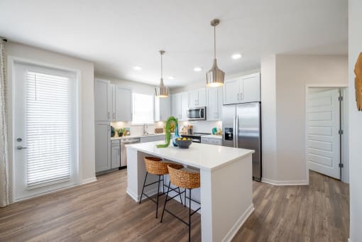 a kitchen with white cabinets and a white island with three stools