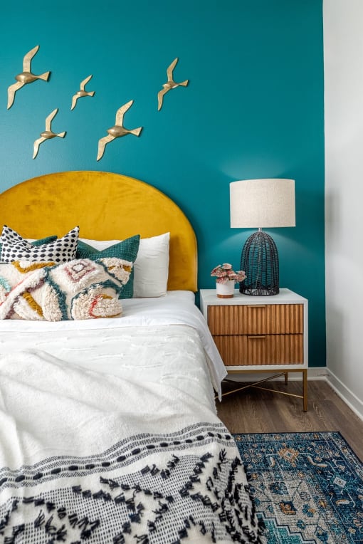 a bedroom with a bed and a blue wall with birds on it