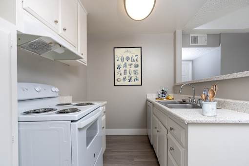 A small white kitchen with a fridge, stove, and sink.