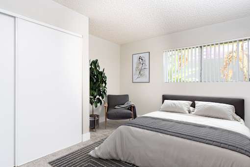 A bedroom with a large bed and a chair.