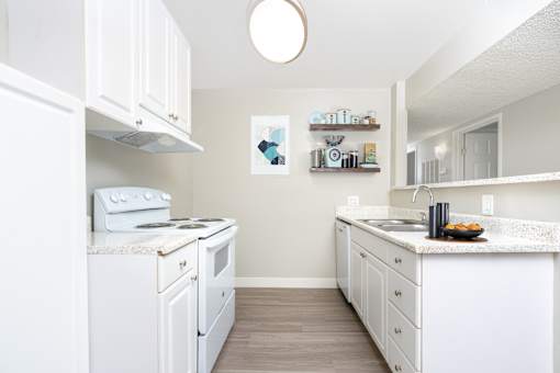 A white kitchen with a stove, oven, and sink.