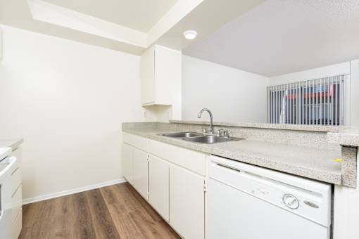 A kitchen with white cabinets and a white dishwasher.