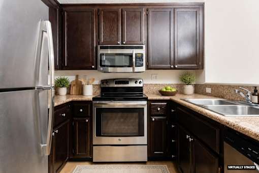 A kitchen with a stainless steel refrigerator, a microwave, a stove, and a sink.