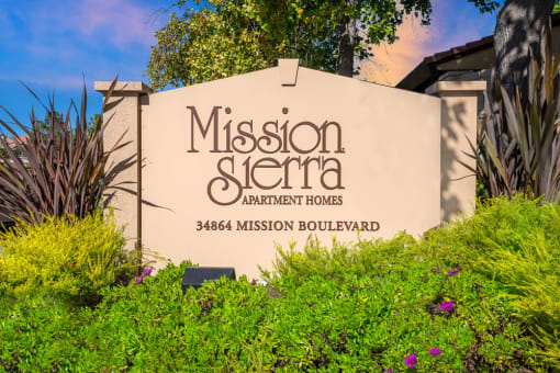 a sign formission sierra apartments sign in front of plants