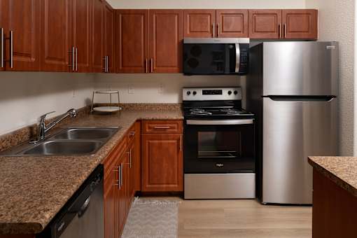 A kitchen with brown cabinets and a stainless steel refrigerator.