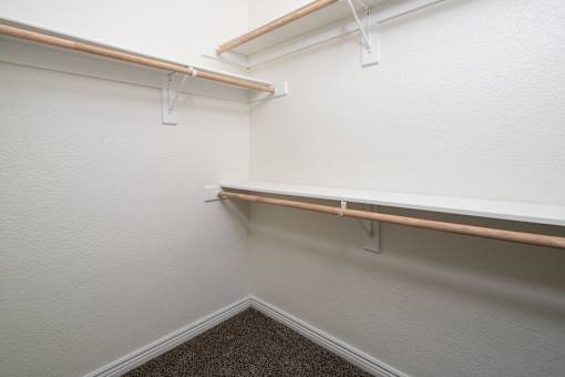 A corner of a room with a carpeted floor and two shelves.