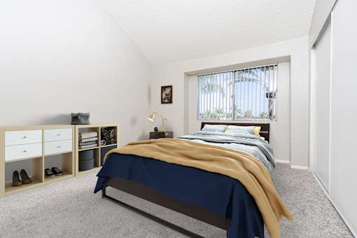 A bedroom with a bed, nightstand, and a window with a view of a tree.
