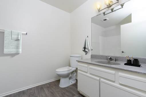 A white toilet sits in a bathroom with a white sink and a mirror.