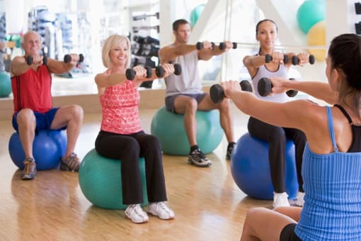 a group of people doing a yoga class with dumbbells