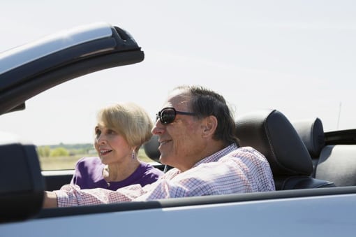 a man and a woman riding in a convertible car