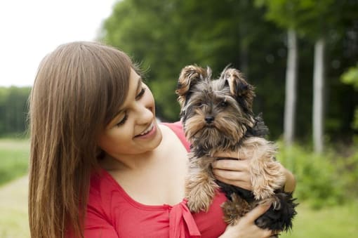 a young woman holding a small dog