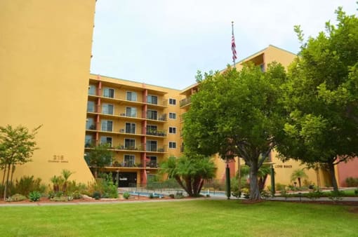 a large yellow building with a lawn and trees in front of it