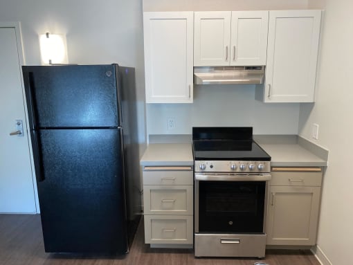 a small kitchen with white cabinets and a black refrigerator