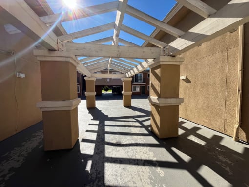 a covered walkway leading to a building with columns and a glass roof