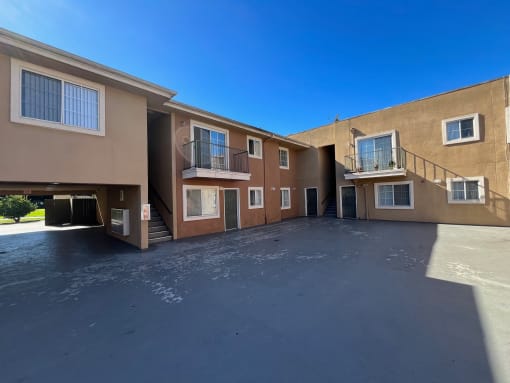 an apartment building with a black driveway and a blue sky
