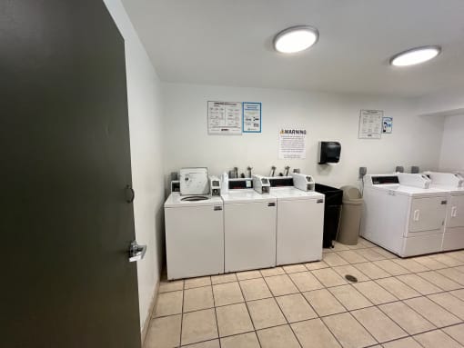 a laundry room with four washer and dryers and a door