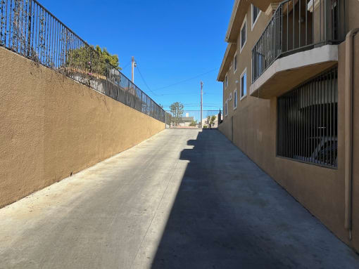 an empty alley between two buildings with a clear blue sky