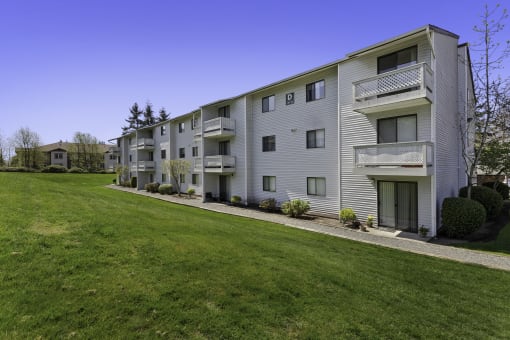 Property View of Apartment Building with Grassy Backyard Area and Wide Open Natural Space at Campo Basso Apartment Homes, Washington