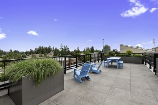 a seating area on the rooftop resident lounge with blue chairs and a table at Arabella Apartment Homes, Shoreline