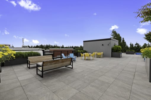 Resident Rooftop Lounge with yellow flowers and benches, chairs, and firepit to lounge by while enjoying rooftop views at Arabella Apartment Homes, Shoreline, WA