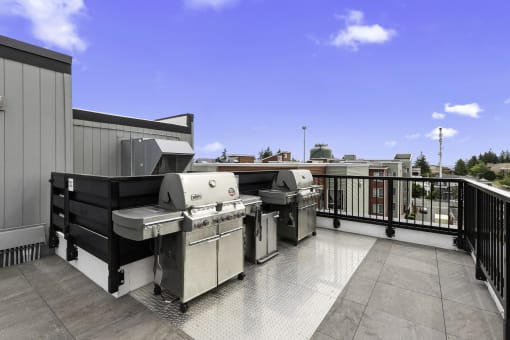 Resident Lounge Area with two barbecue grills and a blue sky in the background at Arabella Apartment Homes, Shoreline, WA