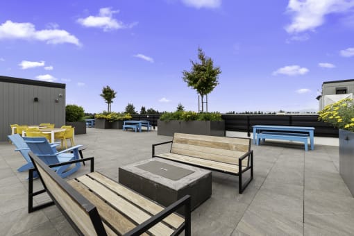 Rooftop Lounge Area with Benches, Blue Adirondack Chairs, and Cozy Firepit at Arabella Apartment Homes, Shoreline, Washington 98155