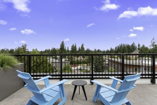 a pair of blue Adirondack chairs in the rooftop lounge area overlooking the view with a table and stool at Arabella Apartment Homes, WA 98155