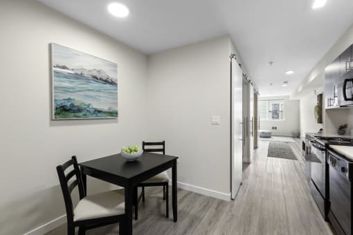 a dining area with a table and chairs and a kitchen in the background at Arabella Apartment Homes, Shoreline, WA