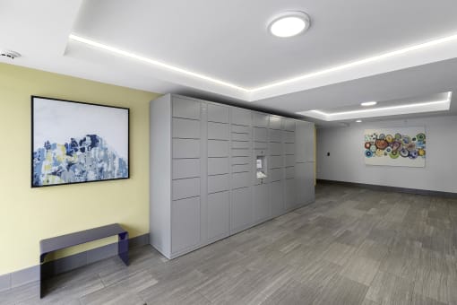 a row of package lockers with a painting on the yellow accent wall at Arabella Apartment Homes, Shoreline, 98155