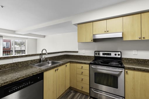 a kitchen with granite-look countertops. wood-look cabinets, and stainless steel appliances at Arabella Apartment Homes, Shoreline, WA
