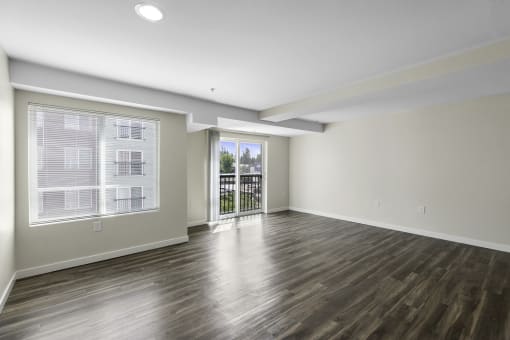 a living room with plank wood-look floors and large windows at Arabella Apartment Homes, WA 98155
