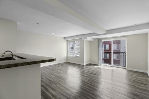 a kitchen and living room in an unfurnished apartment with Large Floor-to-Ceiling Windows and Plank Flooring at Arabella Apartment Homes, Shoreline