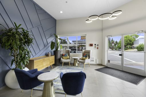 Lobby Area with blue chairs, textured dark blue accent wall, and a wooden desk with a plant in the corner at Arabella Apartment Homes, Shoreline