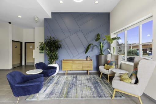 Cozy Lobby Seating Area with blue chairs and a yellow table in front of a textured blue accent wall at Arabella Apartment Homes, WA 98155