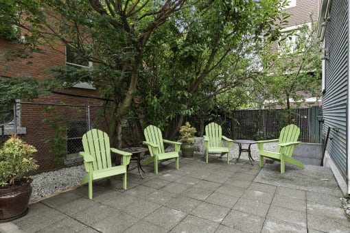 a patio with four green Adirondack chairs and a small table  at Charbern Apartment Homes, Seattle, WA