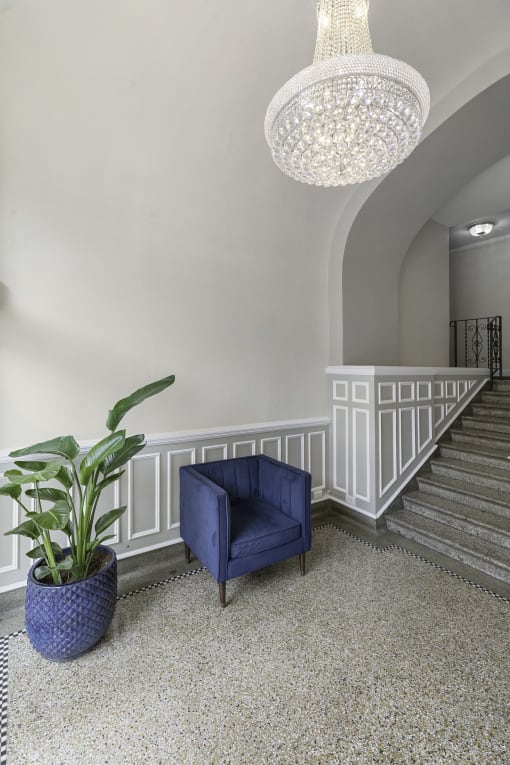 a blue chair sits on a carpeted floor next to a plant and a chandelier at Charbern Apartment Homes, Seattle, WA