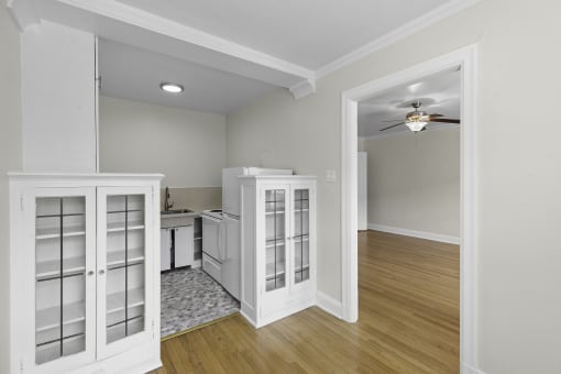 a kitchen and dining room with glass cabinetry, plank flooring, and overhead lighting at Charbern Apartment Homes, Seattle