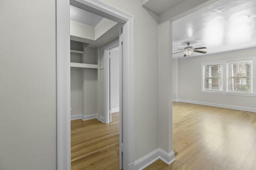 View into a bedroom with hardwood floors and a ceiling fan while also seeing oversized closet space at Charbern Apartment Homes, Seattle, Washington