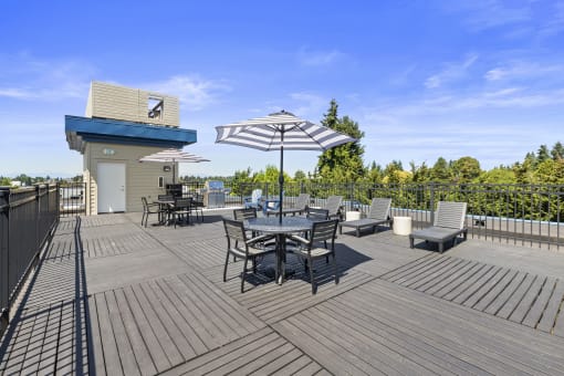 a large outdoor resident deck with chairs and umbrellas at Guinevere Apartment Homes in  Seattle, Washington