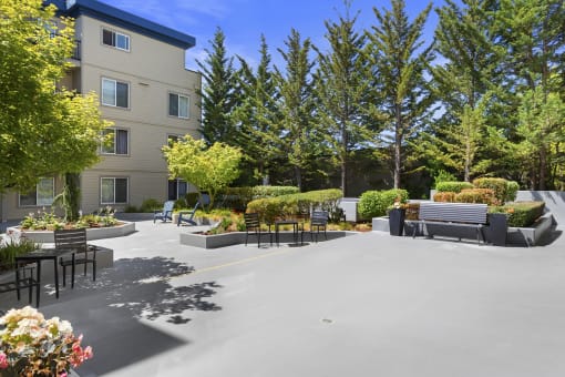 a seating area with benches and trees in front at Guinevere Apartment Homes, WA 98103
