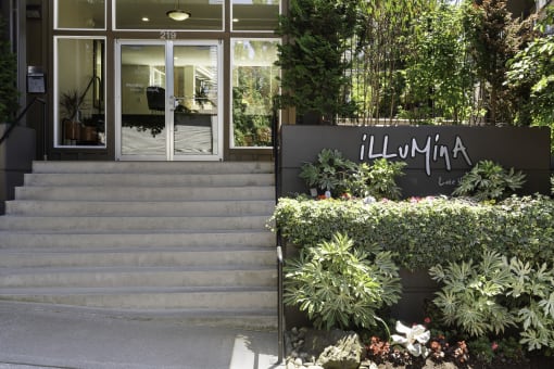 the entrance to the property building with a staircase and plants at Illumina Apartment Homes, Washington