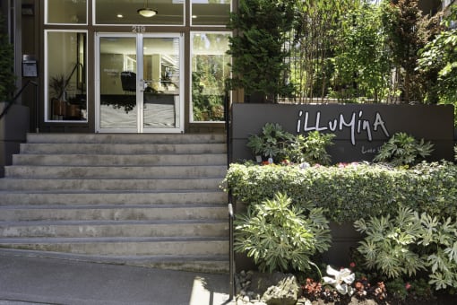 Property entrance with a staircase and manicured plants at Illumina Apartment Homes, Seattle, Washington 98102