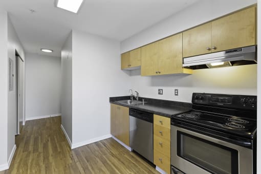 a kitchen with wooden cabinets, plank flooring, and stainless steel appliances at Illumina Apartment Homes, Seattle, 98102