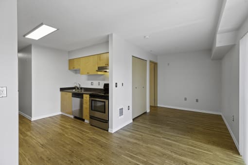 Apartment with a spacious living area and view into the kitchen complete with hardwood floors at Illumina Apartment Homes, Seattle, Washington 98102