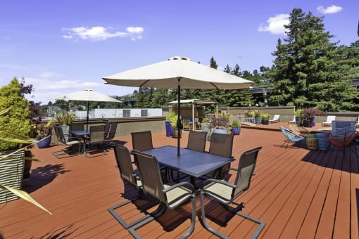 Rooftop wooden deck with tables and umbrellas at Illumina Apartment Homes, Seattle, Washington 98102