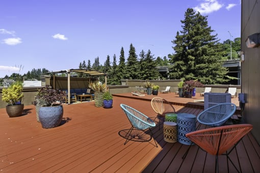 a roof deck with chairs and potted plants at Illumina Apartment Homes, Seattle, 98102